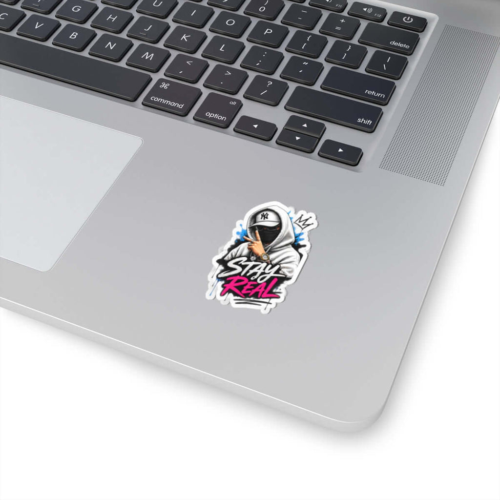 Custom kiss-cut stickers featuring a vibrant 'Stay Real' design on a laptop surface.