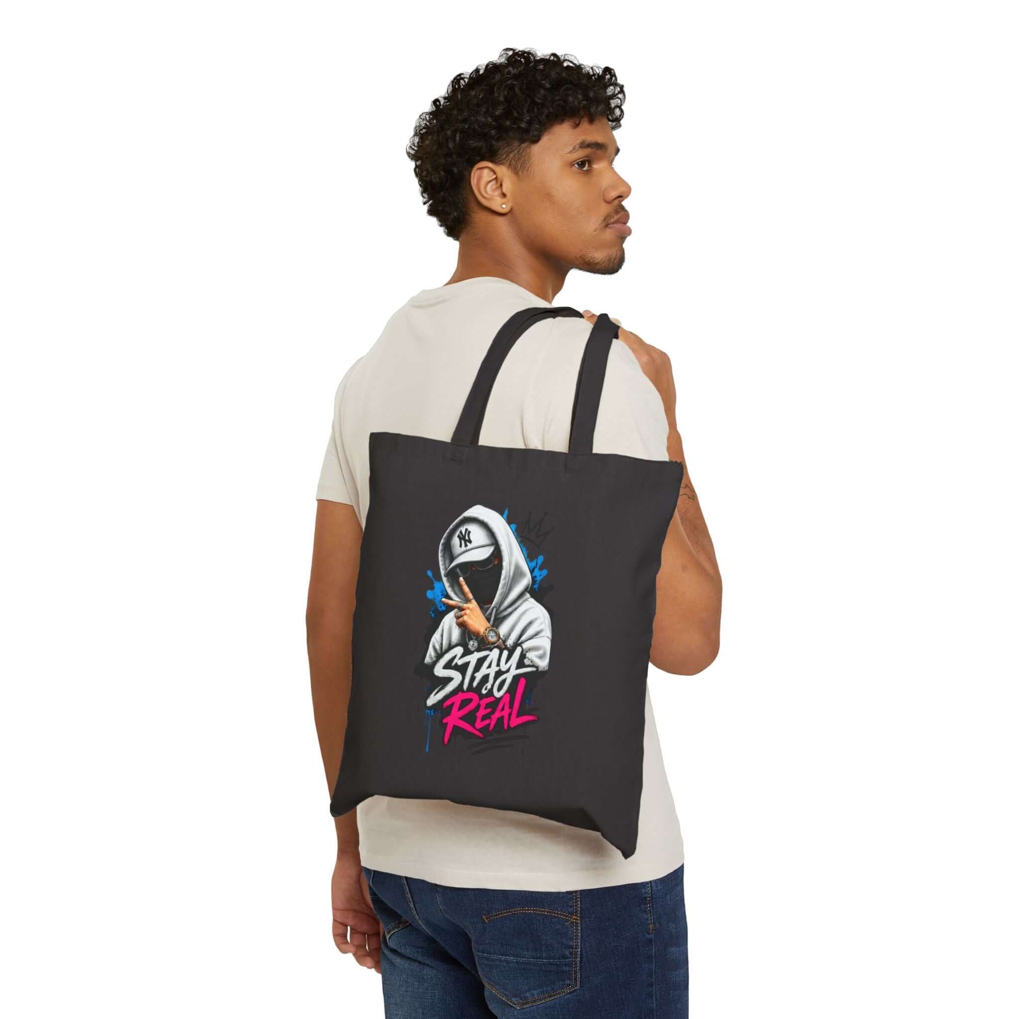 Durable cotton canvas tote bag featuring a stylish graphic design with the phrase 'Stay Real' on a black background.